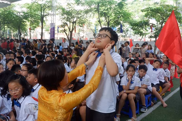 Cô giáo đang chỉnh lại cổ áo cho một học sinh.