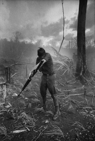 Hình ảnh binh sĩ lấy tay che mặt vì bụi bay mù mịt khi trực thăng chuẩn bị hạ cánh.