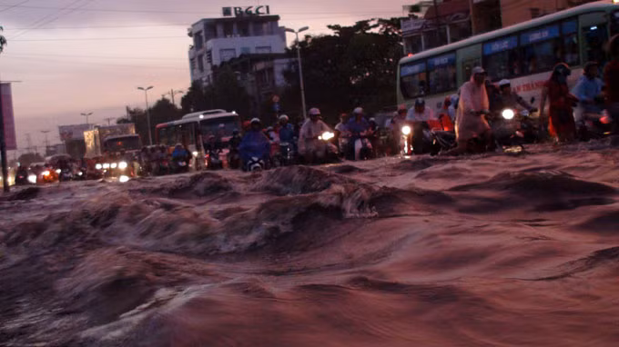 Theo người dân, khi cây ngã xuống, cành lá đè vào chiếc xe máy dựng trên vỉa hè. Khoảng 16h, một cây bàng nằm trước số nhà số 32 đường Văn Thân, P.8, Q.6 đã gãy ngang thân rớt xuống đường khiến tình trạng kẹt xe kéo dài. Trong ảnh là sóng nước trên đường Kinh Dương Vương dâng tới gần thắt lưng.