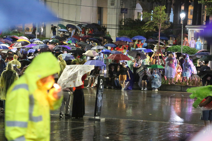 Người dân nghiêm ngắn xếp hàng trong cơn mưa nặng hạt.