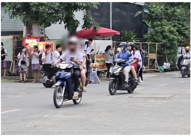 Nam sinh vừa chạy xe máy vừa bấm điện thoại. hsinh-3.png