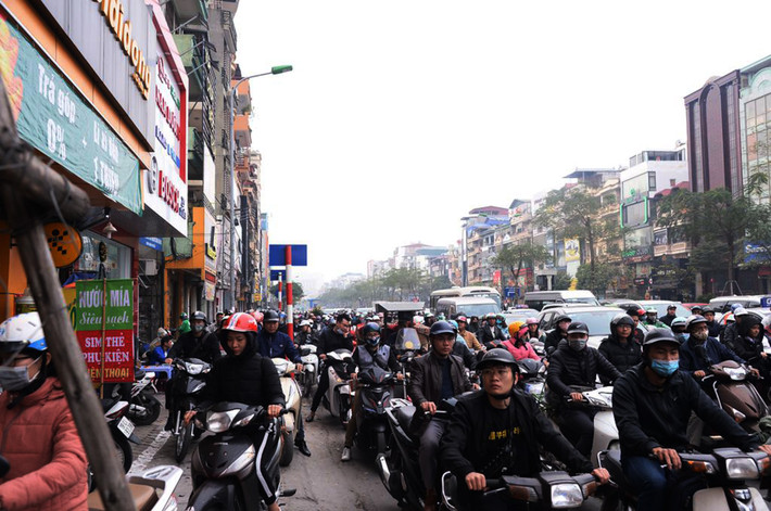 Người đi xe máy đua nhau leo hết lên vỉa hè tìm lối thoát ra khỏi dòng người đông đúc.