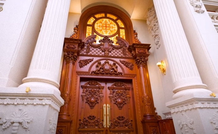 Cửa vào nhà bằng gỗ gõ đỏ, rộng 4,5 mét, cao 7,5 mét, thiết kế riêng biệt, mang tính cá nhân của gia chủ. Ảnh: chụp màn hình NhaTo