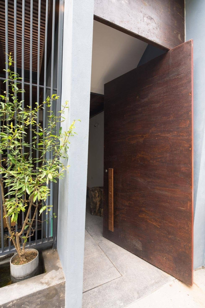 Kirin House có 3 tầng có mặt tiền là khung sắt thoáng đãng và một khu vườn nhỏ. Cánh cổng xoay bằng gỗ to bản. Ảnh: Triệu Chiến