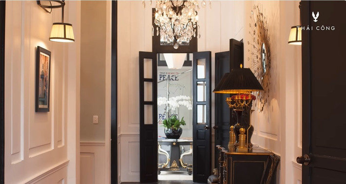 Lối dẫn vào phía trong căn nhà, hành lang với tường ốp gỗ, đèn chùm từ Pháp với pha lê và đồng đen. Ảnh: FBNV