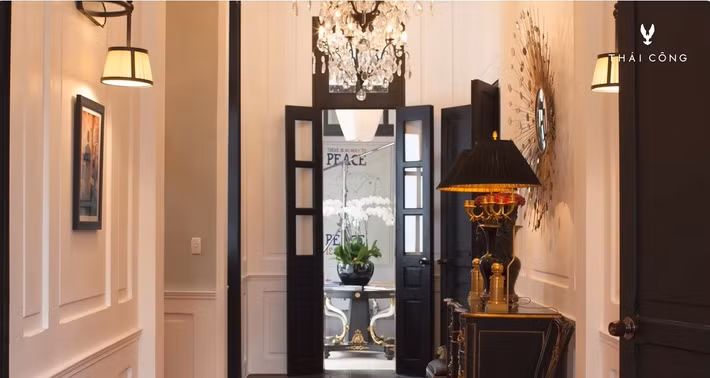 Lối dẫn vào phía trong căn nhà, hành lang với tường ốp gỗ, đèn chùm từ Pháp với pha lê và đồng đen. Ảnh: FBNV