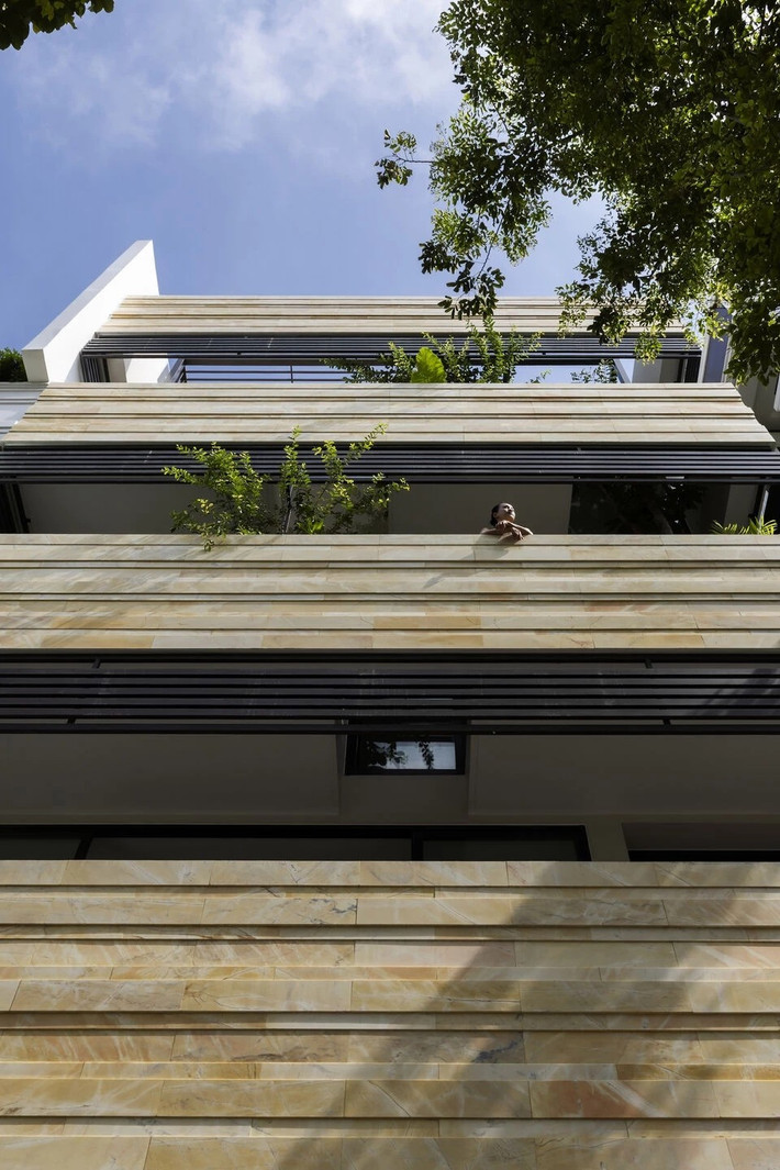 Xen giữa các mảng đá là hệ lam che nắng và mảng xanh được bố trí khéo léo, vừa giúp làm mềm mại nét cứng cáp của vật liệu, đồng thời hạn chế tầm nhìn trực diện, đảm bảo sự riêng tư cho không gian bên trong. Ảnh: Oki Hiroyuki