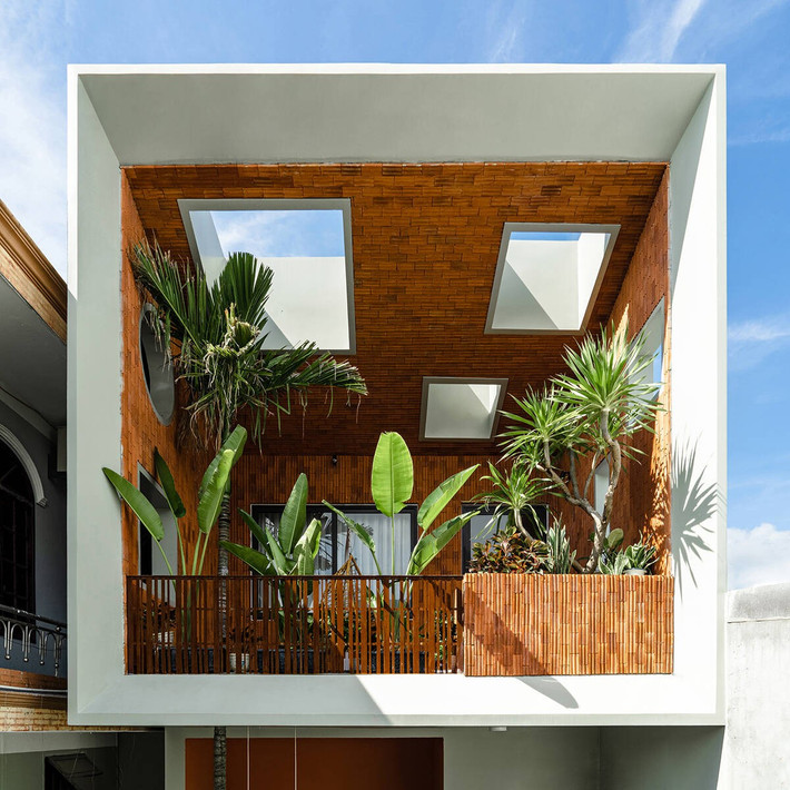 Mặt tiền ngôi nhà nổi bật với khối ban công xanh mát được thiết kế như một khu vườn treo, ẩn mình sau hệ lam gỗ dọc. Ảnh: Phan Trọng Tín - Minh Anh