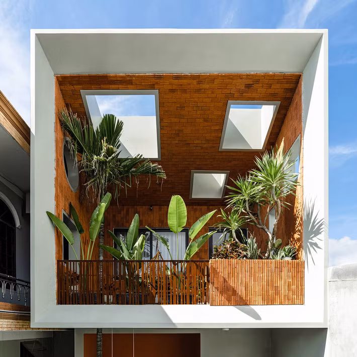 Mặt tiền ngôi nhà nổi bật với khối ban công xanh mát được thiết kế như một khu vườn treo, ẩn mình sau hệ lam gỗ dọc. Ảnh: Phan Trọng Tín - Minh Anh