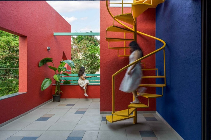 Cầu thang xoắn màu vàng nổi bật trên nền tường xanh - đỏ. Ảnh: Thearchitectsdiary