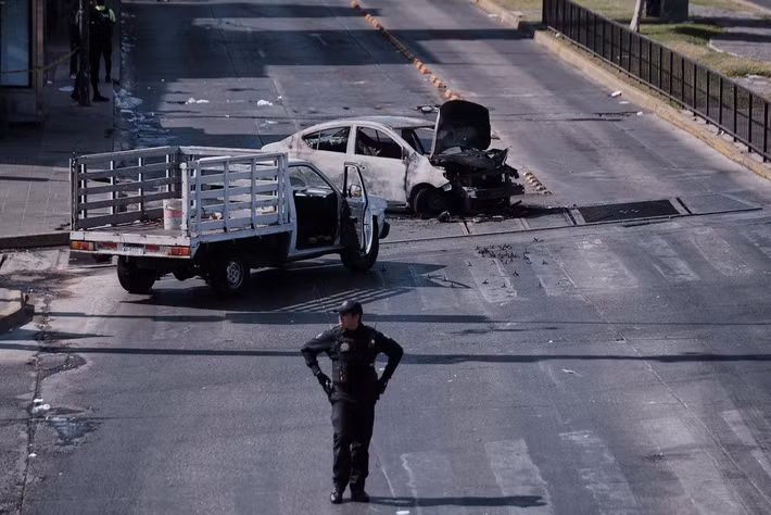 AP đưa tin, Quân đội Mexico ngày 22/2 đã tiêu diệt Nemesio Rubén Oseguera Cervantes có biệt danh "El Mencho" - thủ lĩnh của băng đảng ma túy khét tiếng Jalisco New Generation Cartel và cũng là một trong những kẻ bị Mỹ truy nã gắt gao nhất. Ảnh: Một cảnh sát đứng gác bên cạnh chiếc xe cháy rụi do bị phóng hỏa trên một con đường ở Guadalajara, bang Jalisco, Mexico, ngày 22/2/2026, sau cái chết của trùm ma túy El Mencho. (Nguồn ảnh: AP)