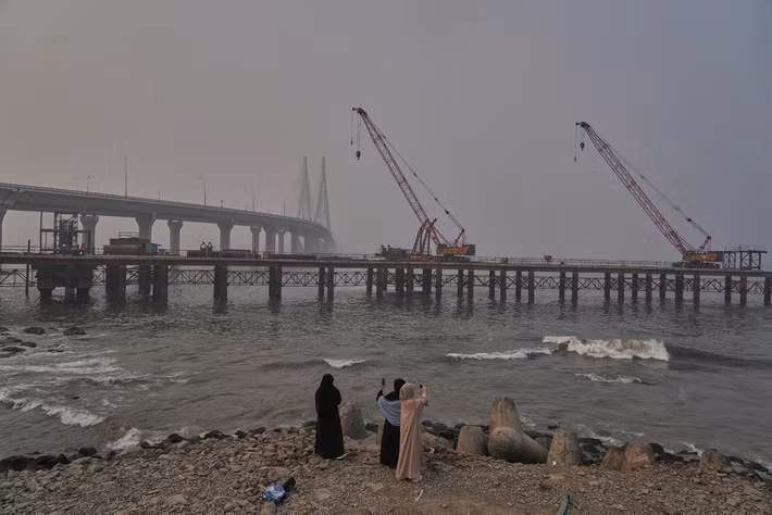 Những người phụ nữ chụp ảnh một công trình đang được xây dựng với cầu vượt biển Bandra-Worli ở phía sau, tại Mumbai ngày 1/2.
