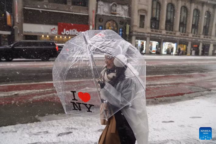 Người phụ nữ che ô đi bộ trên đường phố New York dưới trời mưa tuyết ngày 14/12. Ảnh: Xinhua News.