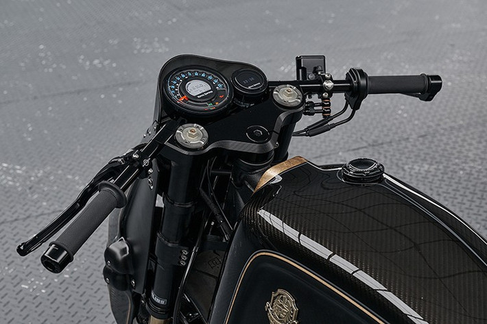 Vẻ ngoài toát lên sự sang trọng với sọc lá vàng thật được phủ bóng màu xám chạy dọc thân xe, nổi bật trên nền đen bóng và đen mờ. Huy hiệu bình xăng bằng đồng thau đúc thủ công – chi tiết được kế thừa trực tiếp từ bản độ nguyên mẫu – trở thành điểm nhấn độc đáo.