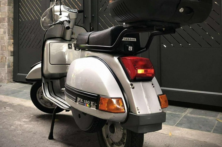 Về ngoại hình, chiếc Vespa PX150E 1995 của vẫn trung thành với kiểu dáng khung thép nguyên khối (monocoque), thân xe liền khối uốn cong mềm mại, chắn bùn trước hình cánh chim và cụm đèn pha hình tròn đặc trưng.