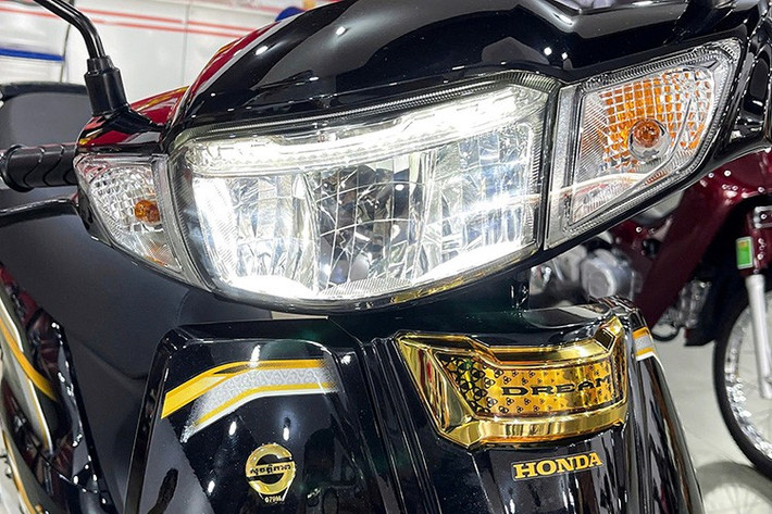 Ngoài bộ tem kèm dòng chữ "Dream" chạy dọc hai bên thân xe, phần góc yếm trước của Honda Dream NCX 2026 còn được trang trí viền tem mới. Phần đầu xe ũng được trang bị đèn LED toàn bộ, bao gồm đèn pha, đèn hậu và đèn xi-nhan phong cách cổ điển, tạo nên vẻ sang trọng nhưng vẫn tiện dụng cho việc sử dụng hàng ngày.