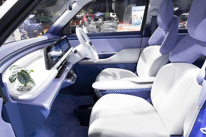 Bước vào bên trong xe, người dùng sẽ bắt gặp không gian nội thất 2 hàng ghế với phong cách thiết kế hiện đại. Nội thất được phối màu xanh lam và tím khéo léo, kết hợp cùng phần dưới ghế trước cũng như bệ tì tay màu be. Ghế trước của Suzuki Vision e-Sky được thiết kế tách đôi trên/dưới, tạo cảm giác thanh lịch và cao cấp. Ở giữa hai ghế này là bệ tì tay tích hợp sạc điện thoại không dây.