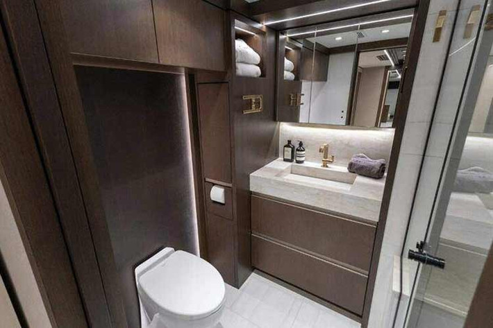 Không gian nhà vệ sinbh của chiếc xe này bao gồm buồng tắm đứng rộng rãi được lát gạch chuyên dụng, bàn đá tự nhiên, bồn cầu hiện đại và hệ thống tủ kệ tăng cường khả năng lưu trữ.