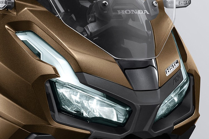 Về ngoại hình, ADV160 2026 vẫn giữ lại dáng vóc đặc trưng của dòng tay ga đa dụng, nhưng có sự tinh chỉnh nhẹ ở phần yếm bên, giúp xe trông cứng cáp và mạnh mẽ hơn. Đèn pha và đèn hậu LED vẫn giữ thiết kế sắc sảo, đồng thời phần chắn bùn phía sau được làm theo phong cách thể thao, tạo nên sự khác biệt so với các mẫu tay ga truyền thống.