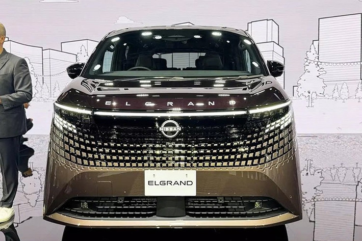 Nhìn chung, bạn sẽ không thể nhầm lẫn phần đầu xe của Nissan Elgrand 2026 với bất kỳ mẫu ôtô minivan nào khác hiện nay. Tại đây, xe được trang bị lưới tản nhiệt lấy cảm hứng từ hoa văn truyền thống Kumiko của Nhật Bản, hòa quyện liền mạch với dải đèn trước.