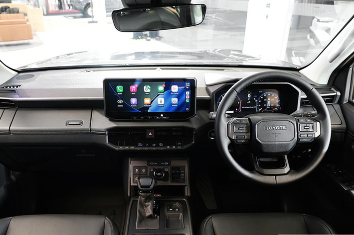 Bên trong, nội thất Hilux 2026 mang thiết kế hiện đại tương tự dòng Land Cruiser, nổi bật với bảng táp-lô trải ngang và cụm màn hình kép 12,3 inch: một cho hệ thống giải trí trung tâm và một cho cụm đồng hồ kỹ thuật số trước vô-lăng.