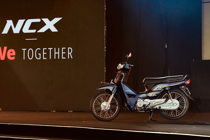 Mẫu xe máy số phổ thông Honda Dream NCX 125i 2026 mang kiểu dáng underbone quen thuộc, được nhấn nhá bởi dải tem Hyper Dynamic Stripe cùng các chi tiết mạ vàng, kim cương nhân tạo và logo NCX nổi bật.