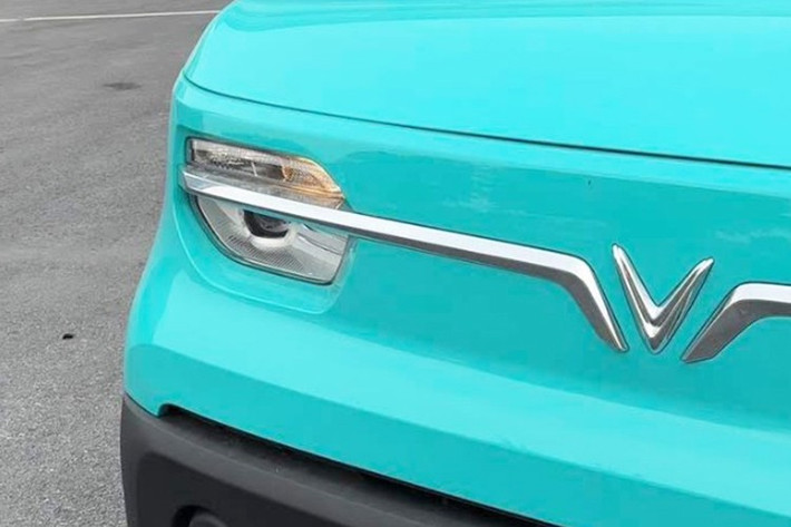 Phần đầu xe nổi bật với thanh crôm tạo hình cánh chim ôm quanh logo “V”, vốn là nét nhận diện chung của nhiều mẫu VinFast. Hệ thống đèn phía trước vẫn sử dụng bóng halogen, trong khi gương chiếu hậu chỉnh cơ dạng cầu tương tự trên mẫu xe mini điện VF3.