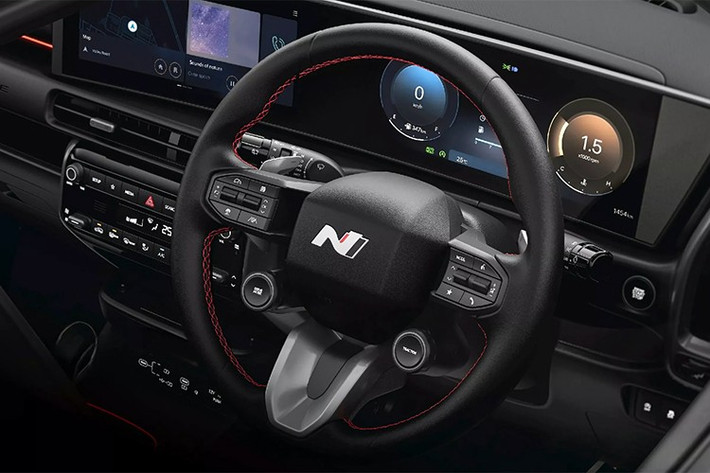 Không gian nội thất được thiết kế theo phong cách thể thao với tông màu đen chủ đạo, điểm xuyết bằng đường chỉ đỏ. Vô lăng có thiết kế tương tự mẫu Ioniq 5 N, tích hợp lẫy chuyển số và núm xoay điều chỉnh chế độ lái.