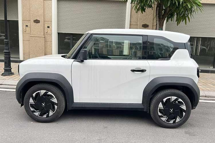 Về diện mạo tổng thể, VinFast VF3 Plus vẫn giữ nguyên kích thước nhỏ gọn và phong cách hình khối đặc trưng. Tuy nhiên, điểm nhận diện dễ dàng nhất nằm ở bộ mâm xe. Thay vì để lộ mâm sắt đơn điệu như các phiên bản trước, bản Plus được trang bị thêm ốp mâm bằng nhựa phối hai tông màu bắt mắt.