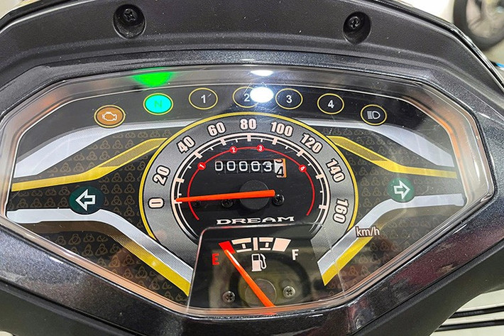 Cụm đồng hồ hiển thị trên Honda Dream NCX 2026 với các đường viền màu vàng trang trí, phân tách thành những khu vực hiển thị thông tin về tốc độ, mức nhiên liệu cùng hệ thống đèn báo… Viền nhựa bao quanh mặt đồng hồ cũng được thiết kế mới và phối màu xám bạc. Hệ thống khởi động vẫn dùng chìa khóa cơ, ổ khóa mở yên xe tích hợp trên phần sau thân xe.