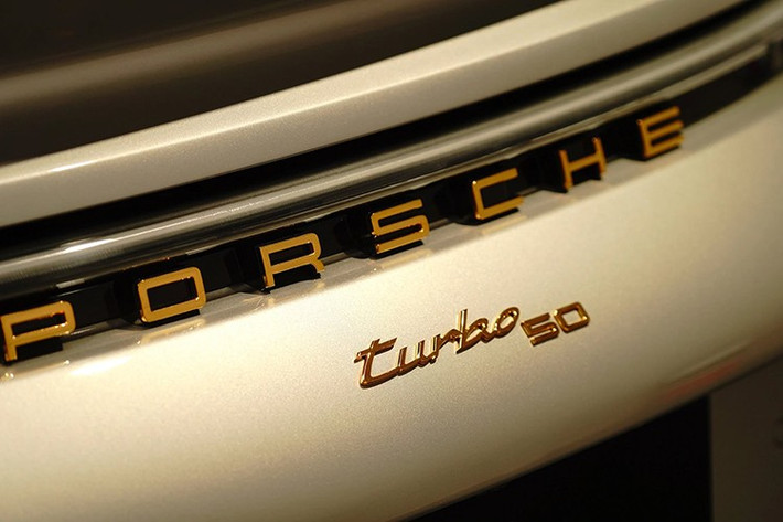 Thiết kế đuôi xe tạo điểm nhấn với dòng chữ "Turbo 50" và "Porsche" được mạ vàng sang trọng. Đèn hậu LED liền mạch được phủ lớp màu xám khói, góp phần tăng vẻ độc đáo cho phiên bản kỷ niệm.