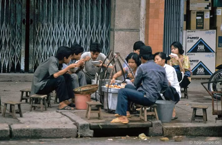 Khách hàng thoải mái thưởng thức đồ ăn đường phố ngay trên nắp cống.