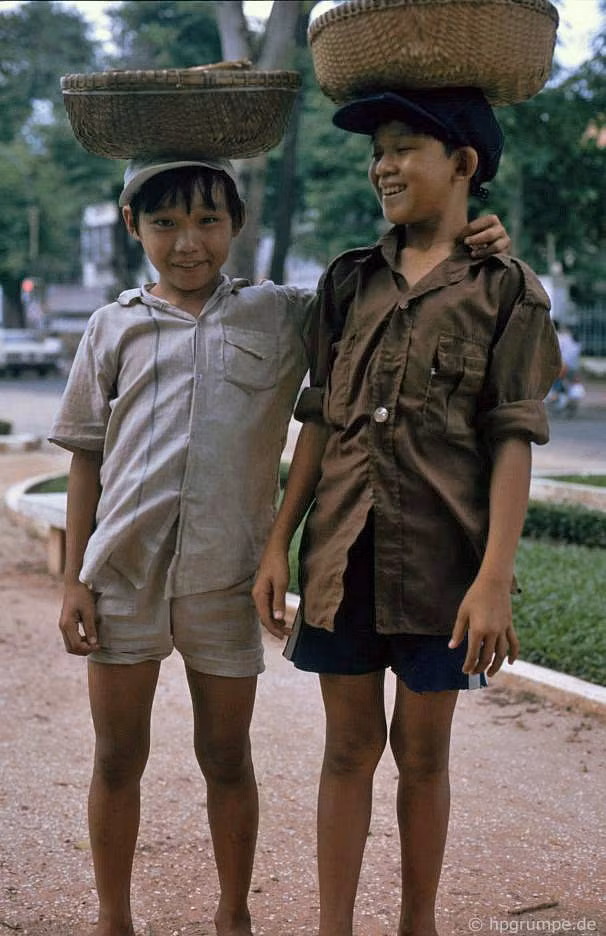 Hâu cậu bé bán quà vặt đội thúng hàng trên đầu.