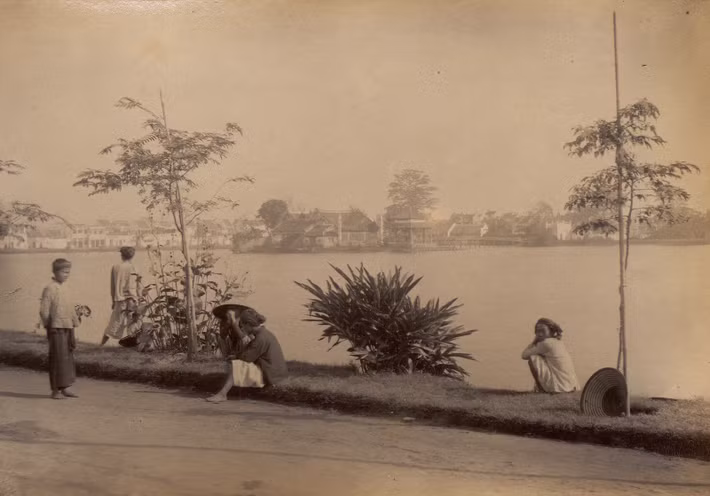 Người dân thư giãn bên bờ hồ, phía xa là đền Ngọc Sơn.
