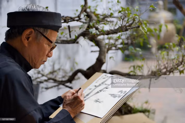 Họa sĩ kiêm nhà thư pháp cao tuổi vẽ tranh bằng mực tàu bút lông ở khu phố cổ Hà Nội.