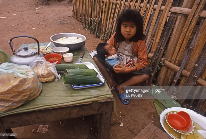 Bé gái vừa chăm em, vừa trông quầy hàng nhỏ.