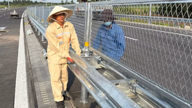 Công nhân kiểm tra, hoàn thiện lưới gắn lan can trên cao tốc trước giờ thông xe. Ảnh: QUÝ HIỀN.