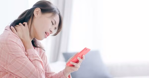 Không chỉ ảnh hưởng đến mắt, việc sử dụng điện thoại sai tư thế còn là nguyên nhân hàng đầu dẫn đến các vấn đề về cổ và cột sống. Khi cúi đầu xuống khoảng 45 độ để nhìn màn hình trong nhiều giờ liên tục, phần cổ phải chịu một áp lực lớn hơn nhiều lần so với tư thế thẳng tự nhiên, khiến cơ cổ và vai nhanh chóng rơi vào trạng thái căng cứng.